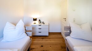 Un dormitorio con dos camas, una mesita de noche, una lámpara y un aparador.