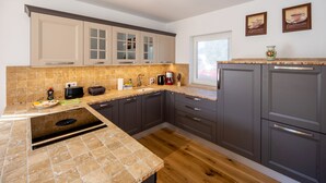 Una cocina moderna con gabinetes grises, salpicadero de azulejos y piso de madera.