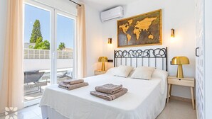 A bedroom with a large bed, two bedside lamps, a world map artwork, and a view of the outdoors.