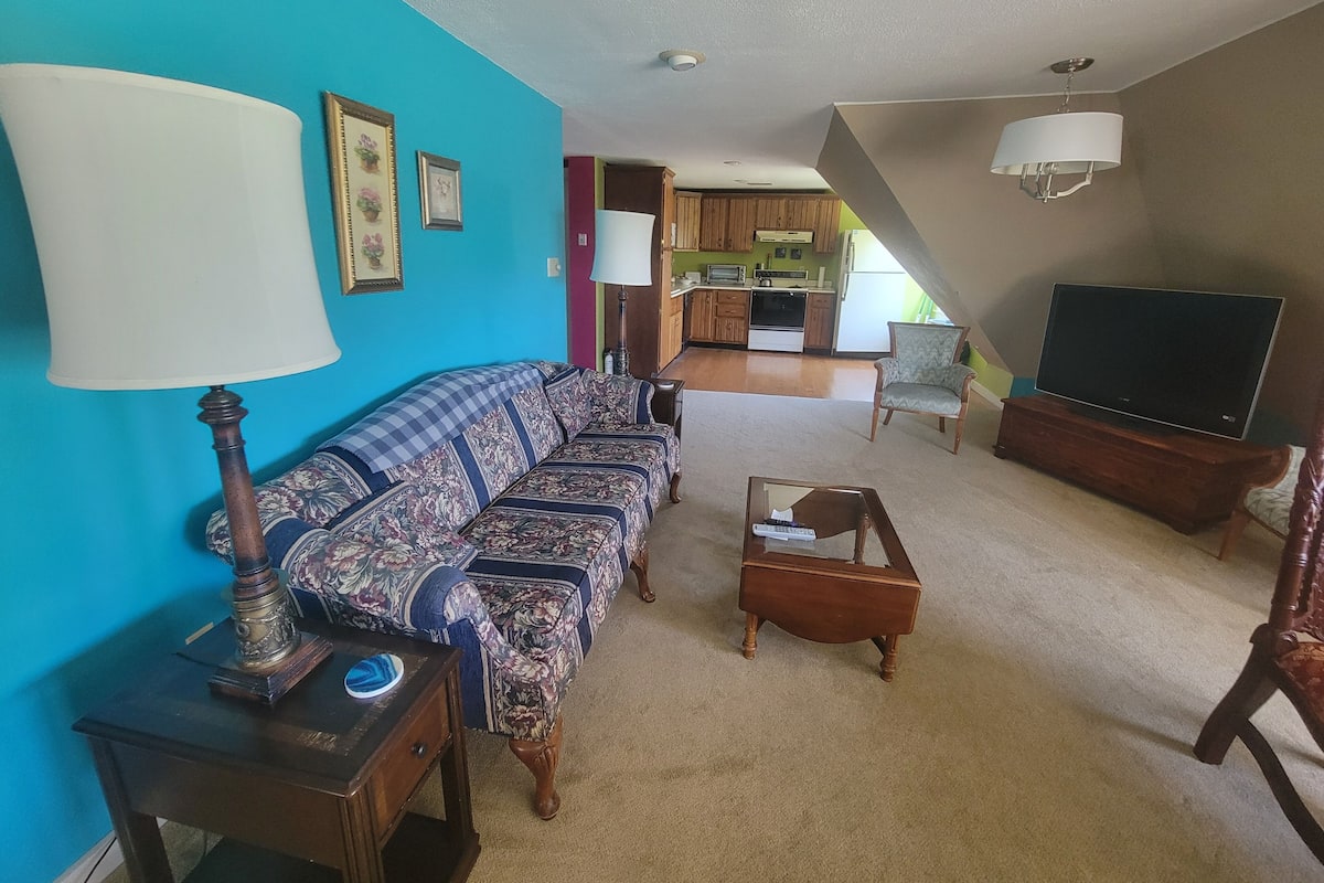 A living room with a sofa, a television, a lamp, and a small table.