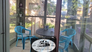 A covered patio area with a table and chairs, a sign indicating 'The Weis Mansion Bed & Breakfast', and a view of the surrounding neighborhood. - The Weis Mansion (Waterloo)