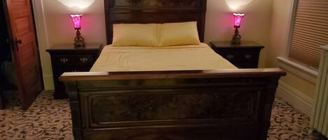 A wooden bed with a headboard, two bedside tables with lamps, and patterned carpet.