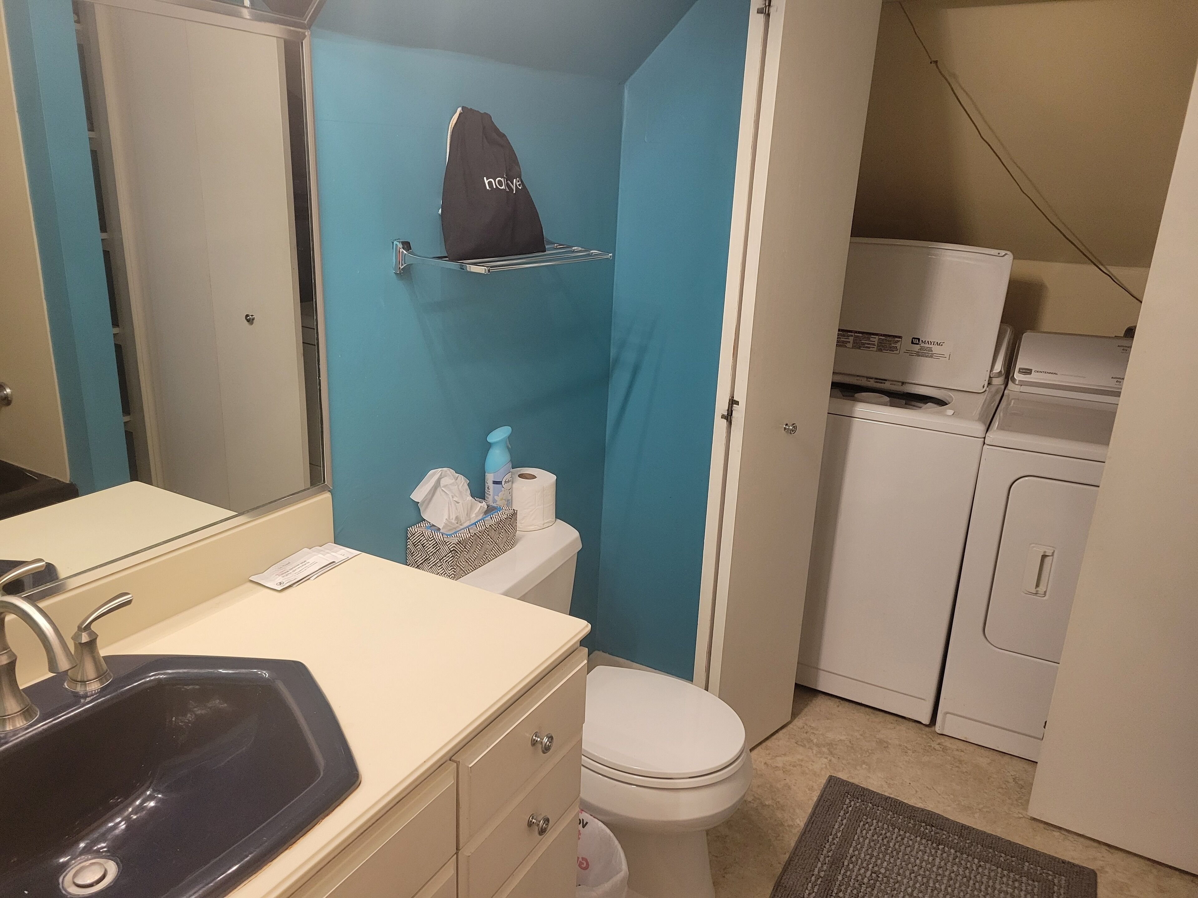Un baño compacto con lavamanos, inodoro y una pequeña zona de lavandería.