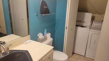 Un baño compacto con lavamanos, inodoro y una pequeña zona de lavandería.