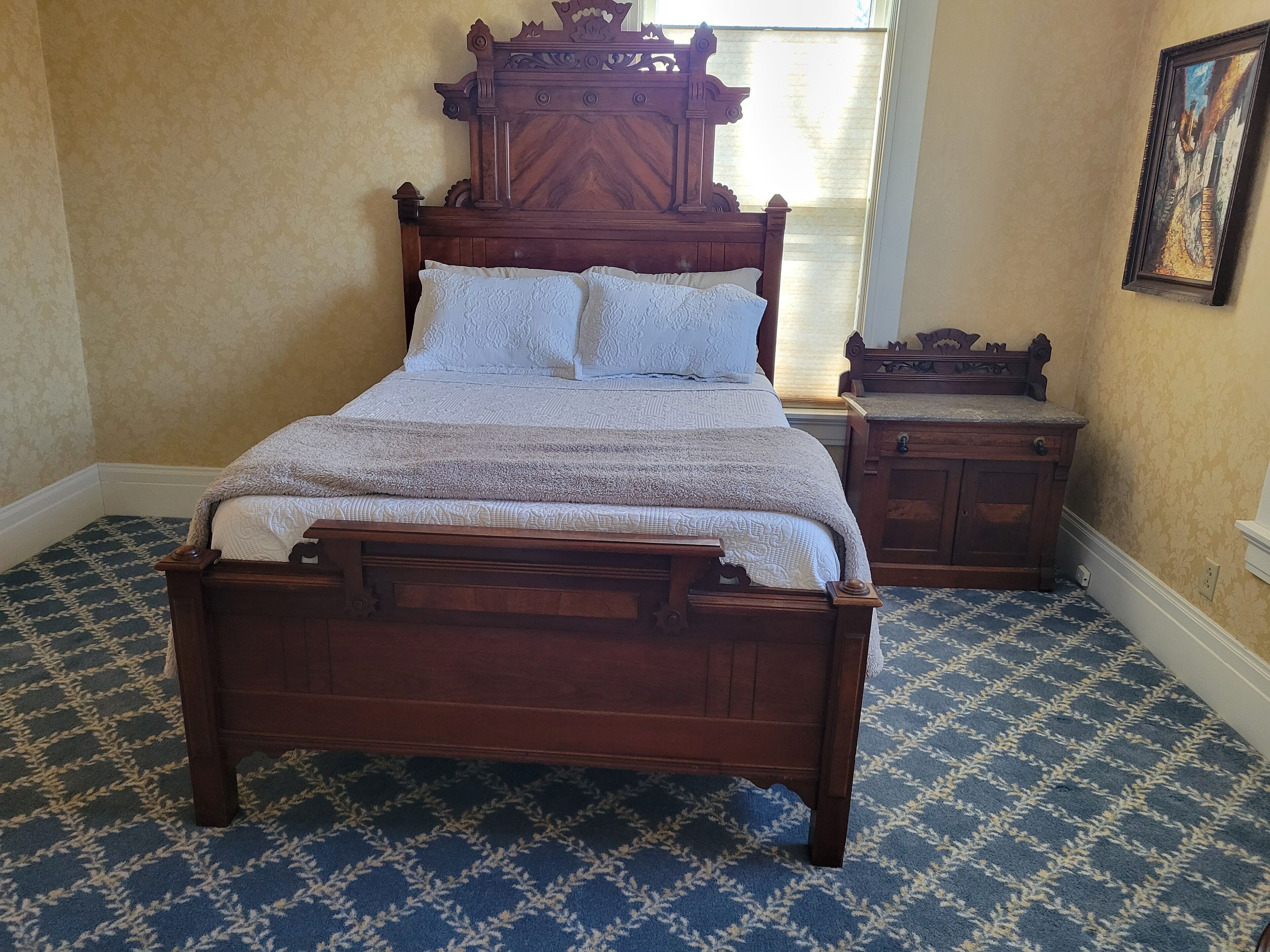 Una cama de madera tradicional con un cabecero, una mesita de noche a juego y una alfombra estampada.
