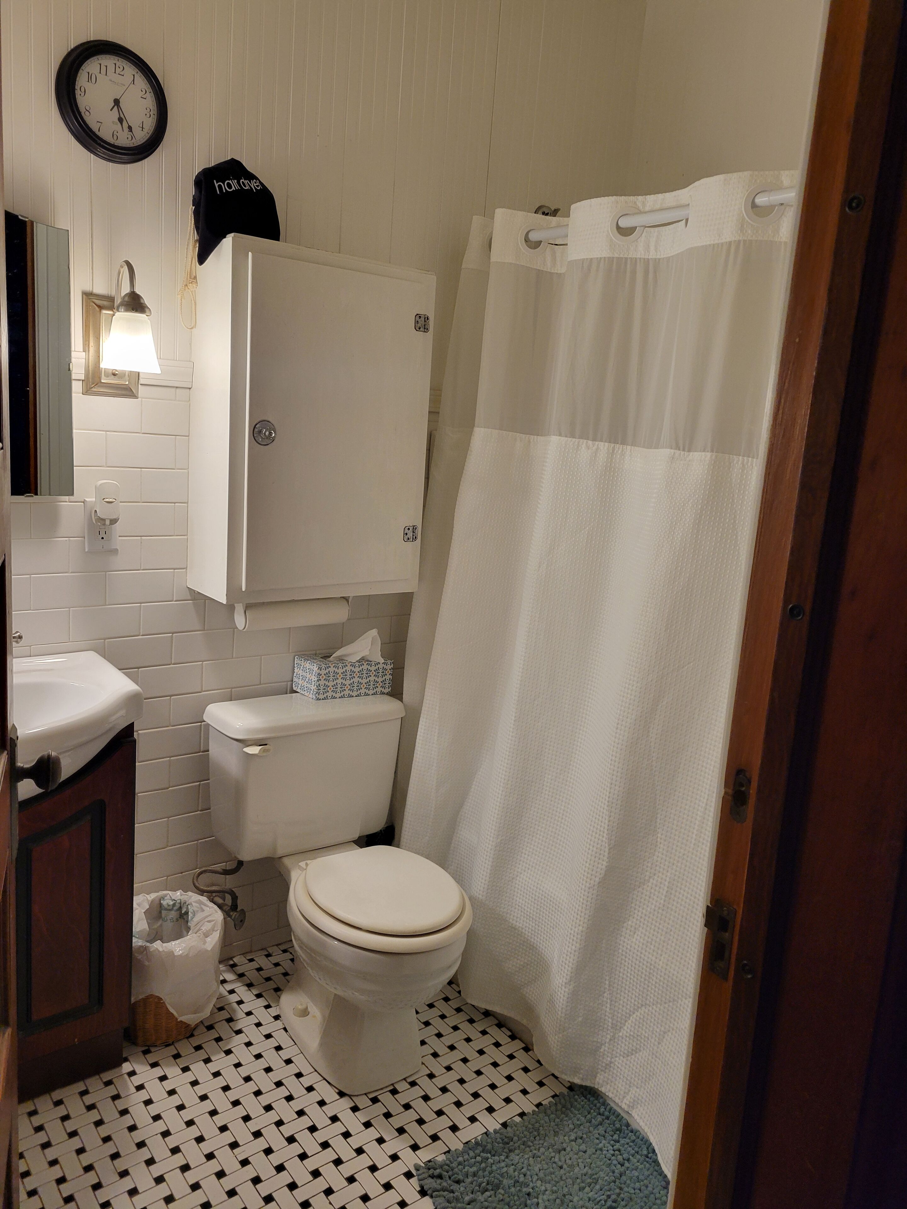 Un baño con inodoro, lavabo y cortina de ducha.