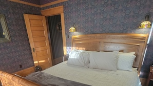 A wooden bed with a headboard, a wooden door, and a patterned carpet. - The Weis Mansion (Waterloo)