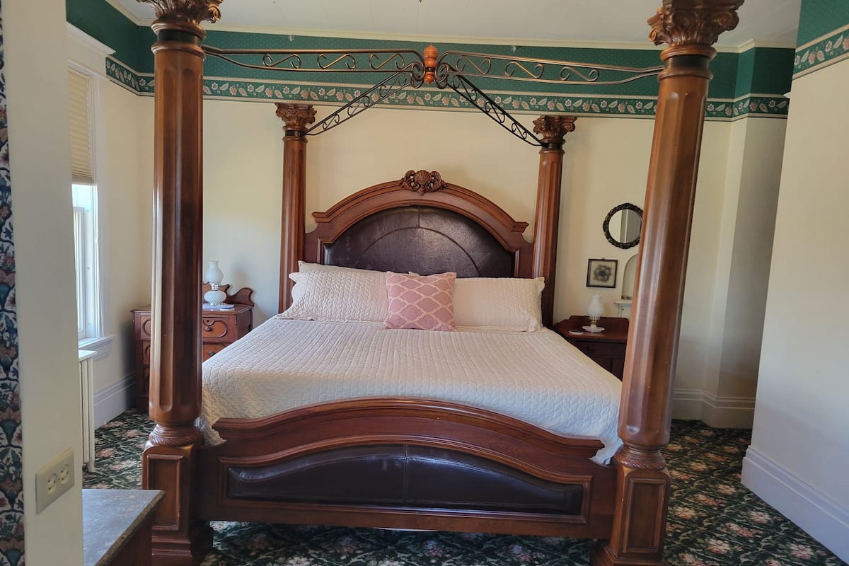 A four-poster bed with a wooden frame and a floral-patterned carpet.