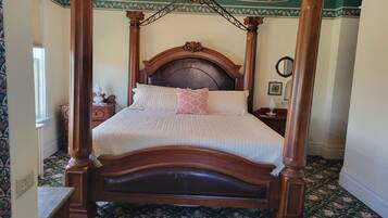 Una cama con dosel de madera y una alfombra con estampado floral.