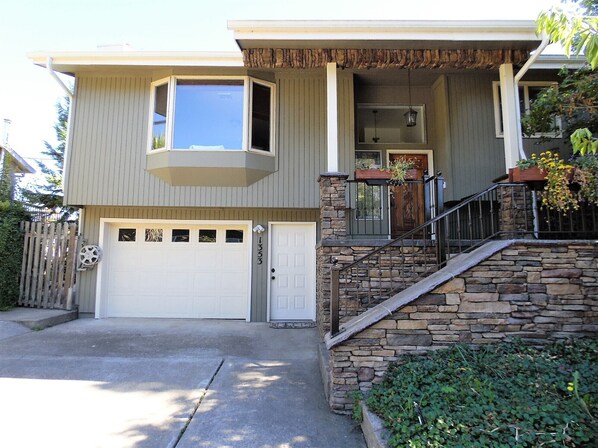 A two-story house with a stone staircase, a garage, and a small balcony.
