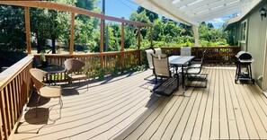 A wooden deck with outdoor furniture, including a table and chairs, and a grill.