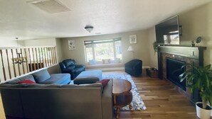 Un salón espacioso con un sofá grande, chimenea, televisión y comedor.