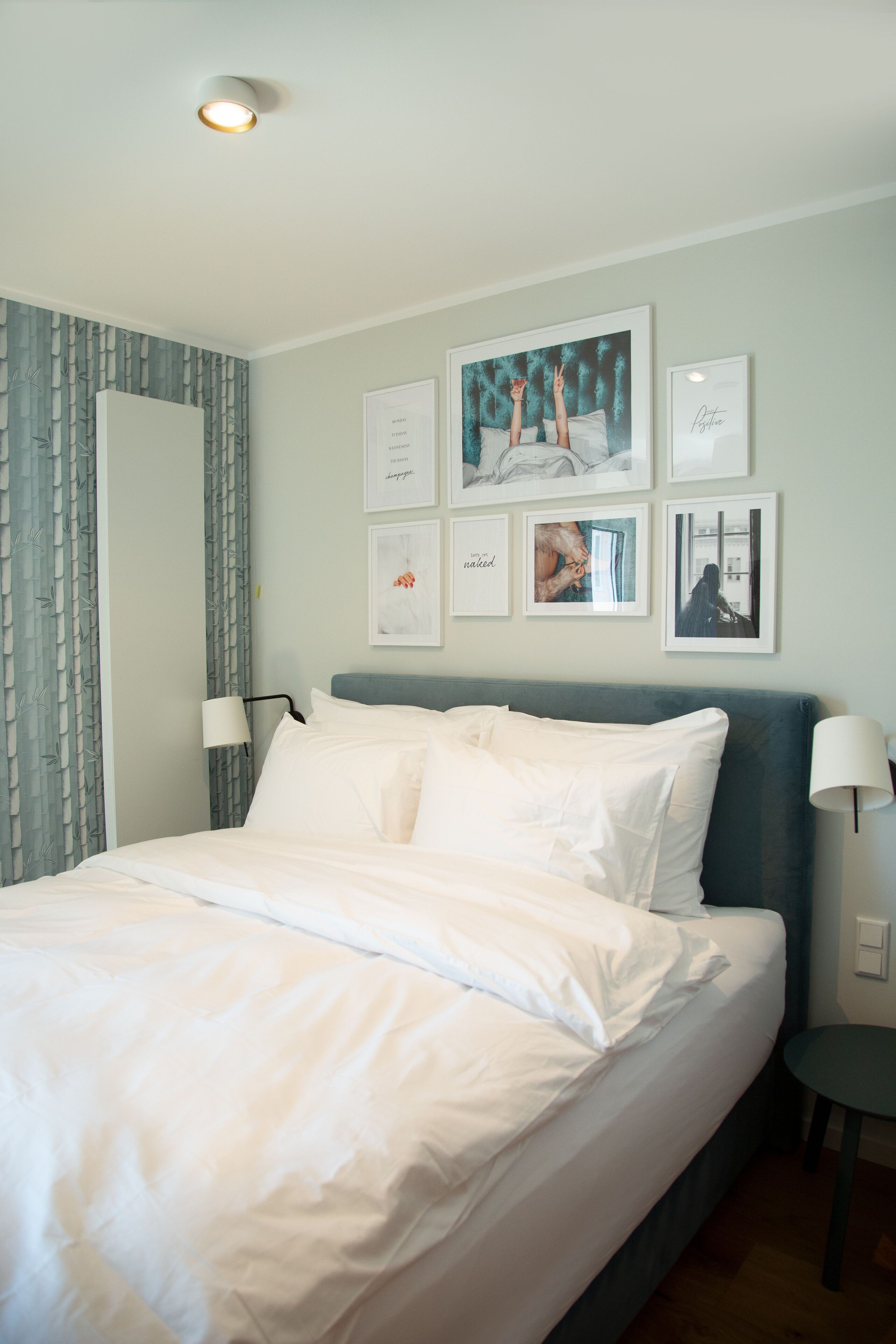 A neatly made bed with white linens, a headboard, and two bedside lamps.