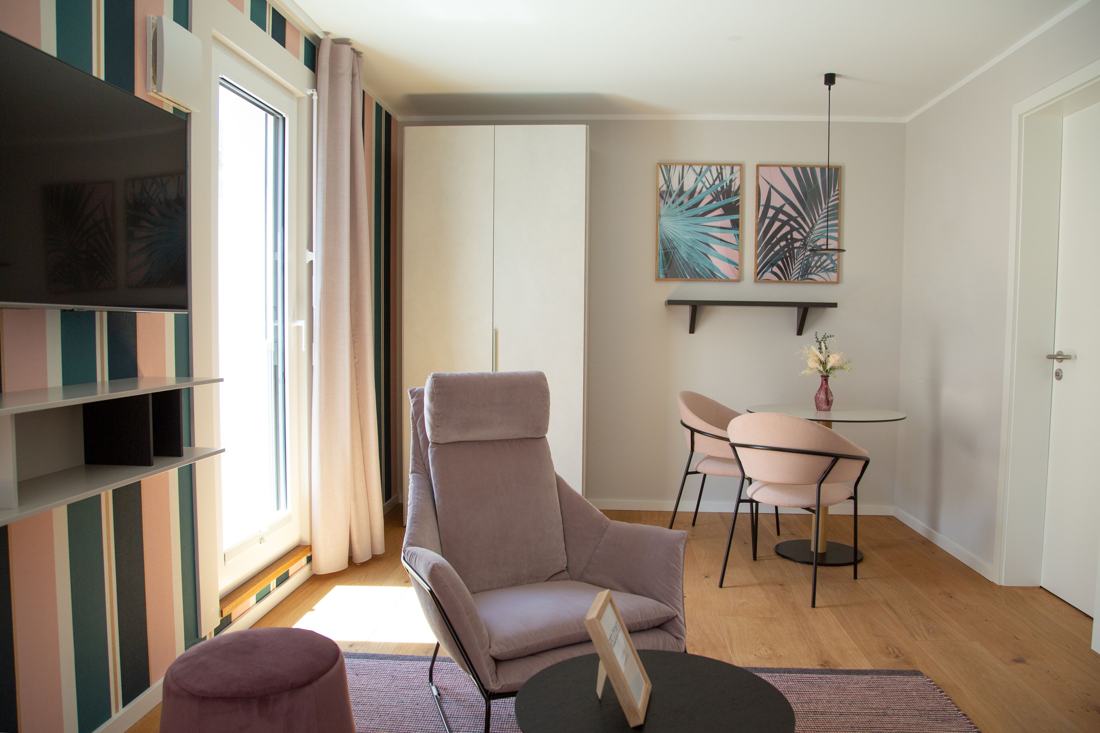 Ein modernes Wohnzimmer mit einer Couch, einem Esstisch mit Stühlen, einem Fernseher und einem Bücherregal.