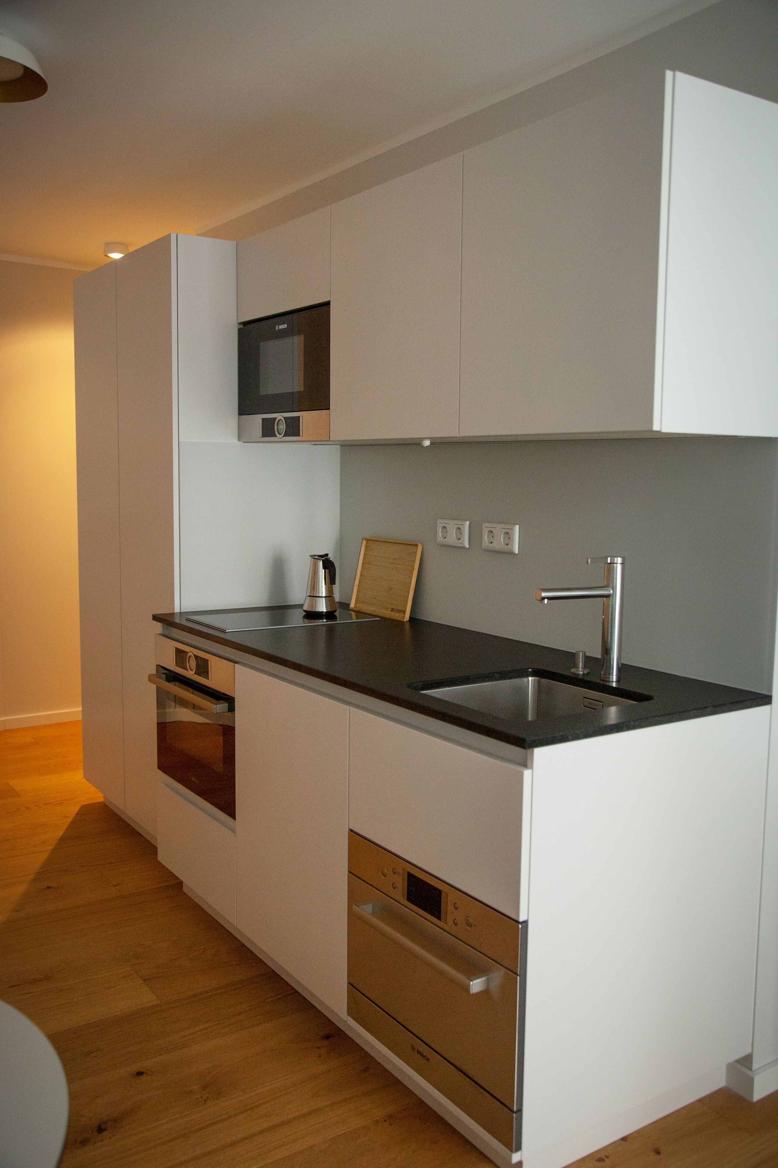 A modern kitchen with white cabinets, a stainless steel sink, and a built-in microwave.