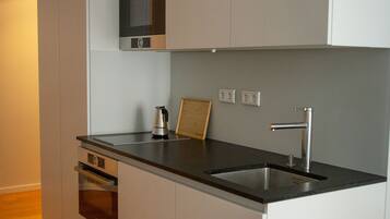 A modern kitchen with white cabinets, a stainless steel sink, and a built-in microwave.