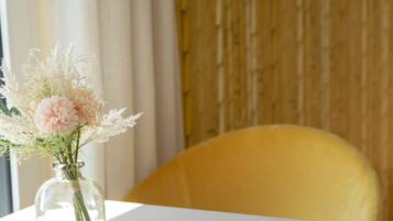 Ein Tisch mit Blumen in einer Vase, ein gelber Stuhl und ein Holzboden.