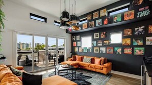 Ein modernes Wohnzimmer mit einer schwarzen Wand, die mit gerahmten Postern verziert ist, einem Ecksofa und einem Couchtisch.