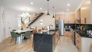 Eine moderne Küche mit einer zentralen Kochinsel, Holzschränken und einem eingebauten Backofen.