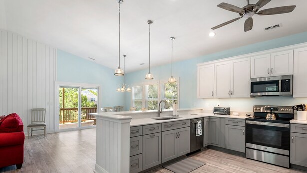 A modern kitchen with white cabinets, stainless steel appliances, and a large island. - Tranquility Cove: New Build, Elevator, Pool Access (Nags Head)