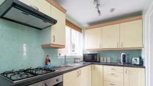 A kitchen with a gas stove, microwave, sink, and cabinets.