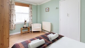 A bedroom with a bed, a chair, a radiator, and a wardrobe.