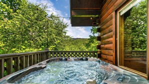 Ein Whirlpool mit einer Holzterrasse und Blick auf einen bewaldeten Bereich.
