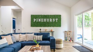 Ein Wohnzimmer mit blauem Sofa, einem Couchtisch und einem an der Wand befestigten Schild mit der Aufschrift "PINEHURST".