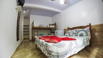 A compact room with a bunk bed, a ceiling fan, a small desk, and a refrigerator.
