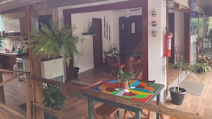 A cozy room with a wooden table, chairs, and potted plants. - Suítes Cantinho da Pedra (Angra dos Reis)