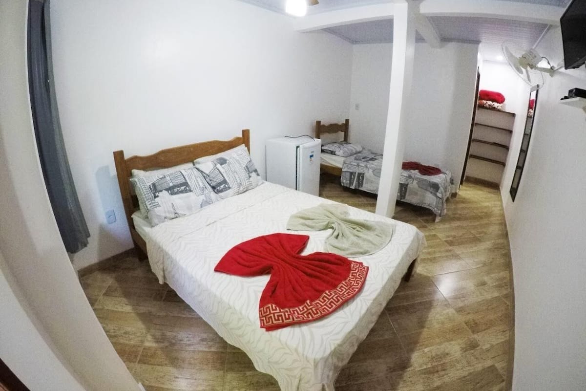 Een slaapkamer met een bed, een plafondventilator en een klein wit apparaat.