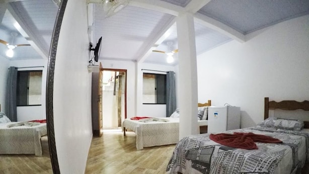 A room with two beds, a refrigerator, and a ceiling fan. - Suítes Cantinho da Pedra (Angra dos Reis)