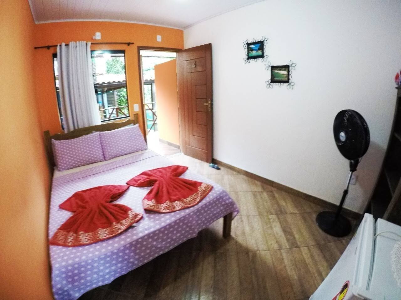A bedroom with a bed, a fan, and a window with curtains.
