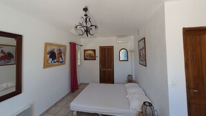 Een slaapkamer met een bed, een plafondventilator en een raam.