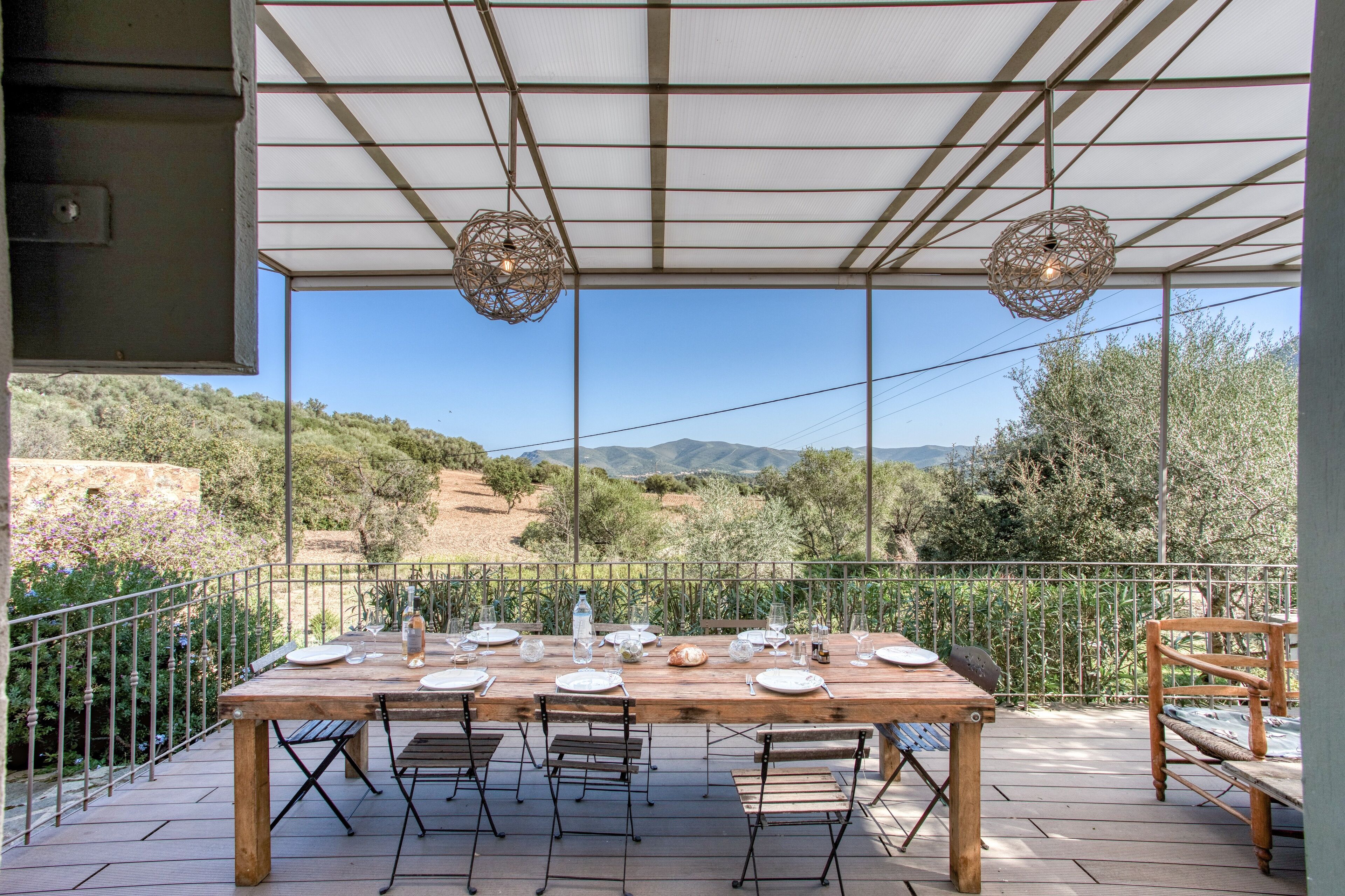 A wooden table set for dining with a view of the countryside.