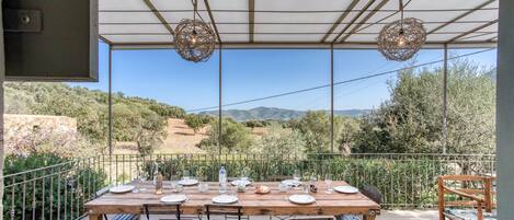A wooden table set for dining with a view of the countryside.