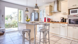 A modern kitchen with a central island, stainless steel appliances, and a view to the outside.