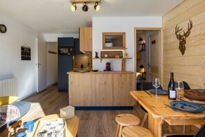 Una cocina acogedora con armarios de madera, una isla central y una zona de comedor con una mesa dispuesta para dos.