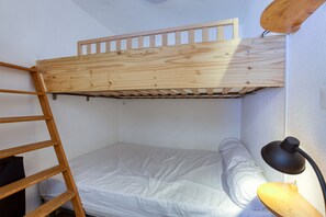 Una cama litera con una escalera de madera y una lámpara de escritorio.