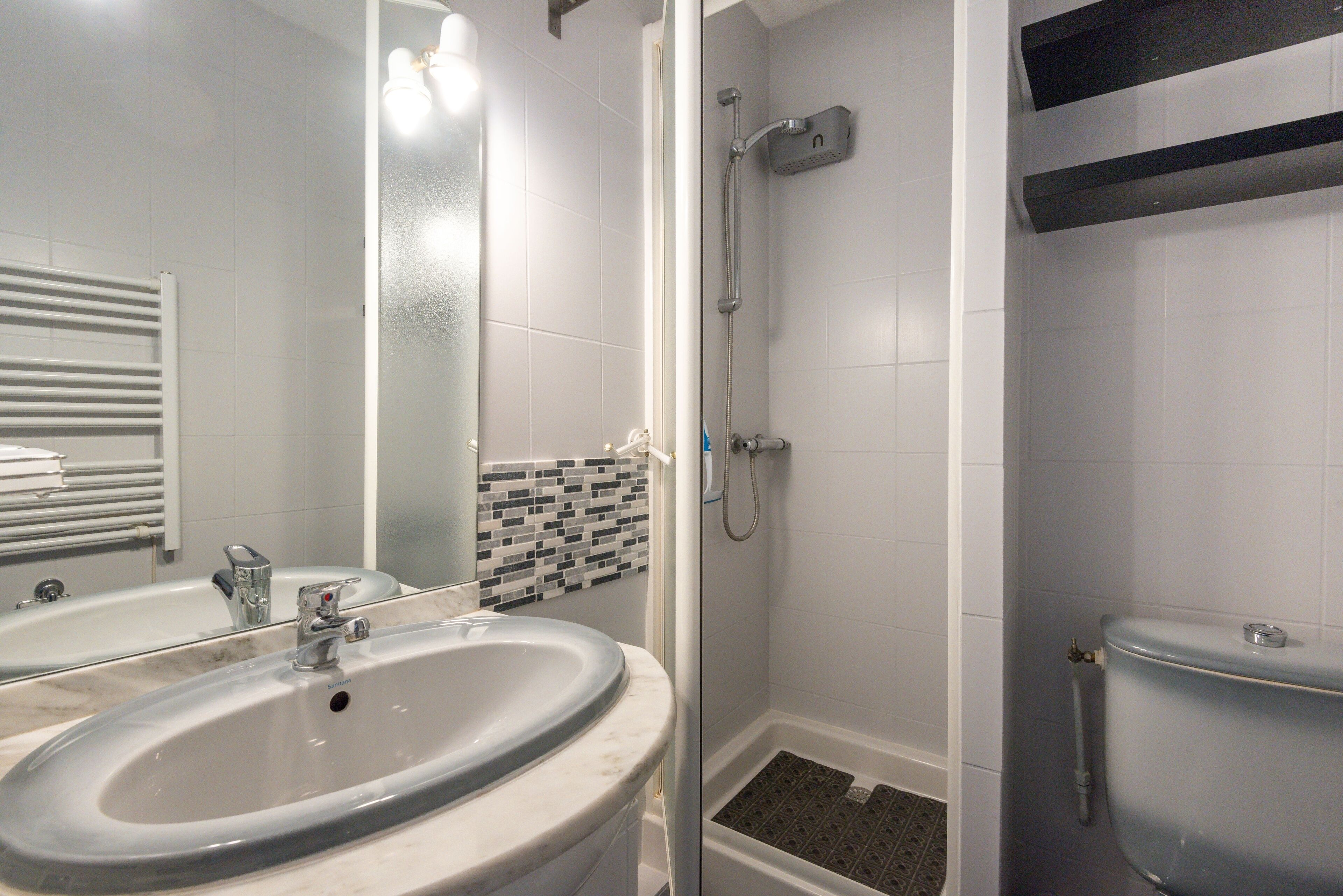 A bathroom with a sink, mirror, shower, and toilet.