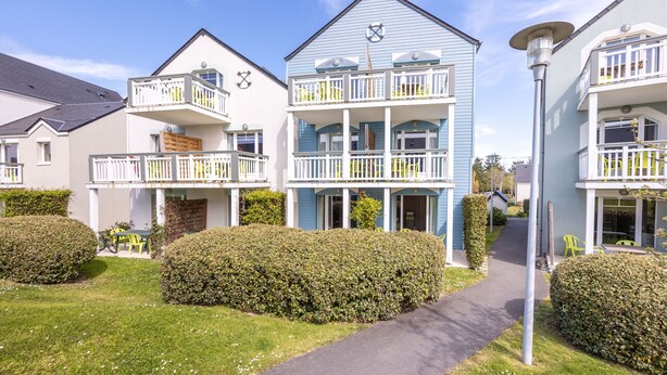 A row of two-story houses with balconies, a paved walkway, and well-maintained hedges. - Danou - Appartement avec Terrasse (Courseulles-sur-Mer)