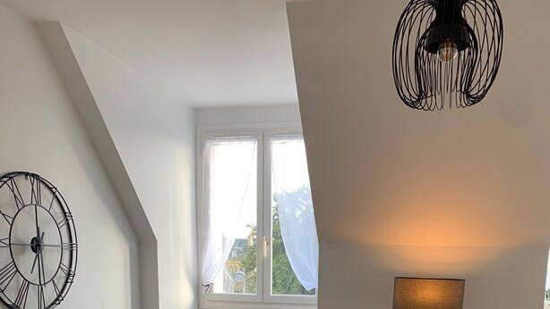 A modern living room with a grey sofa, a wooden coffee table, a round rug, a wall clock, and a lamp.