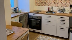 A compact kitchen with a wooden countertop, white cabinets, a built-in oven, and a patterned backsplash.