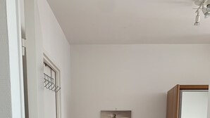 A bedroom with a wooden dresser, a bed, and a wall-mounted artwork.