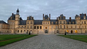 A historic building with a symmetrical facade, a central staircase, and a paved courtyard.