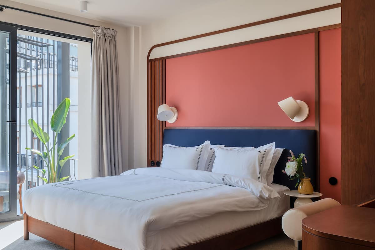 Camera d'albergo moderna con un letto grande, una scrivania e vista sull'esterno.