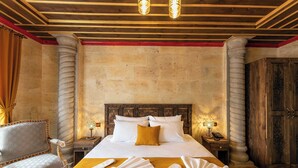 A hotel room with a large bed, two bedside tables, a wooden wardrobe, and a chair. - Volare Stone Hotel (Nevsehir)