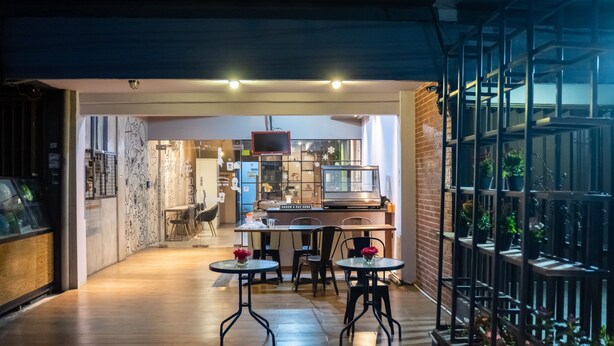 A modern interior with a kitchen area, dining space, and a staircase leading to an outdoor area with plants. - Sahaja Pasar Baru (Jakarta)
