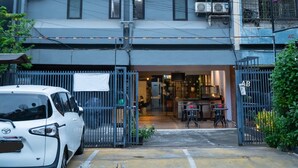 A multi-story building with a gated entrance, air conditioning units, and a neon sign. - Sahaja Pasar Baru (Jakarta)