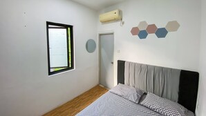 A bedroom with a bed, a window, an air conditioner, and a wall decoration. - Sahaja Pasar Baru (Jakarta)
